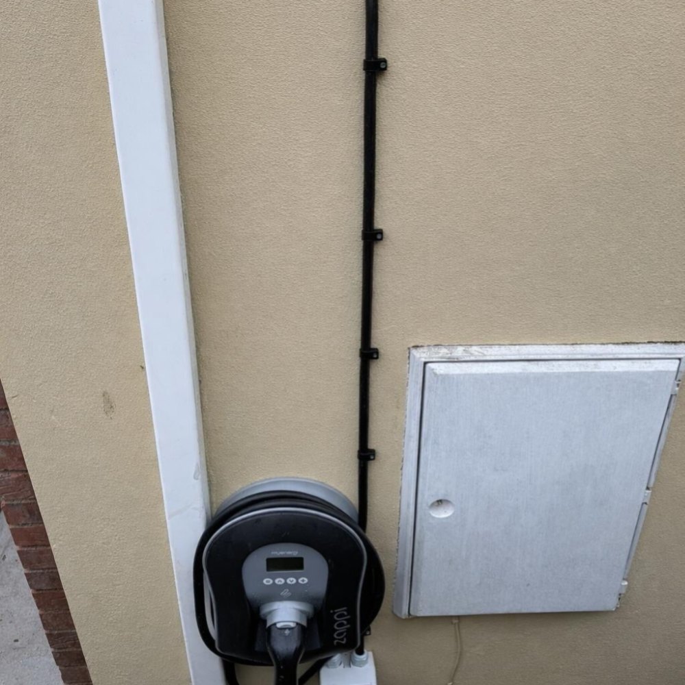 An EV charger beside a meter box on a rendered wall
