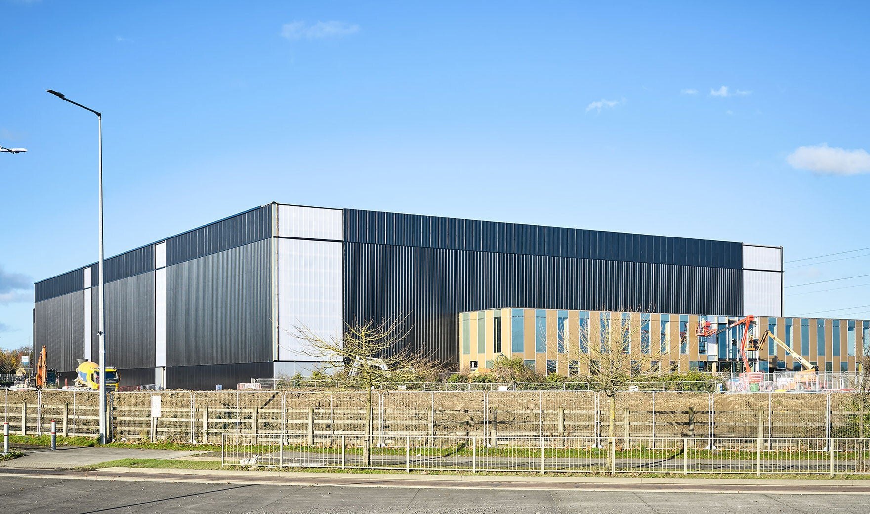 A large industrial building with dark cladding under a blue sky